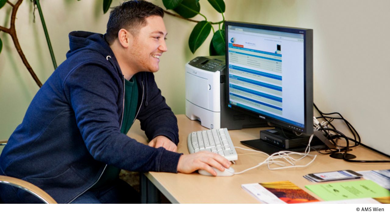 Junger Mann am Schreibtisch vor PC Monitor